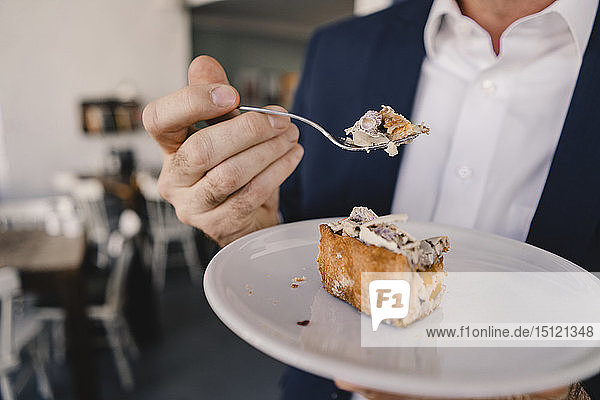 Close-up of businessman having a piece of cake in a cafe