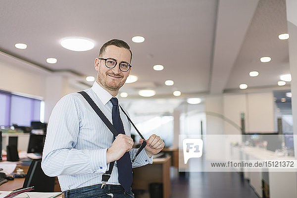 Portrait of confident businessman posing with suspenders at the office