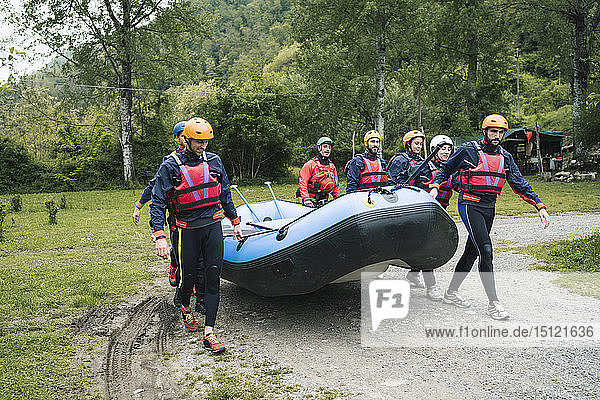 Eine Gruppe von Freunden bereitet sich mit einem Schlauchboot auf eine Rafting-Tour vor