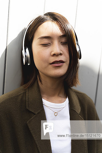 Relaxed young woman with closed eyes listening to music with headphones