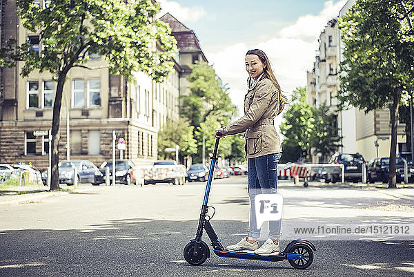 Porträt einer lächelnden Frau mit E-Scooter in der Stadt
