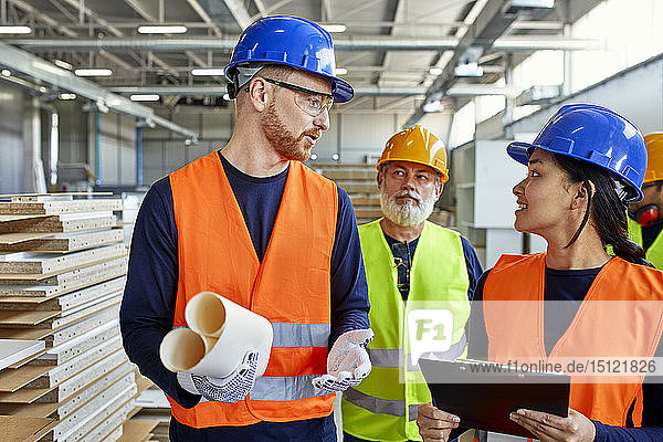 Colleagues in protective workwear talking in factory