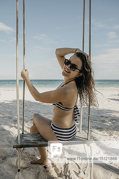 Mexico Quintana Roo Tulum happy young woman on a swing on the beach