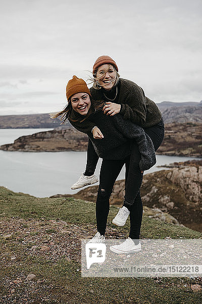 Grossbritannien  Schottland  Hochland  glückliche Frau  die ihren Freund huckepack durch die ländliche Landschaft trägt