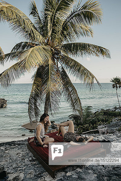 Mexiko  Quintana Roo  Tulum  zwei glückliche junge Frauen entspannen sich am Strand