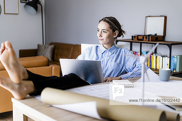 Woman in office working on laptop with feet on table