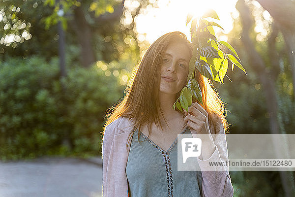 Junge rothaarige Frau mit Blättern in einem Park