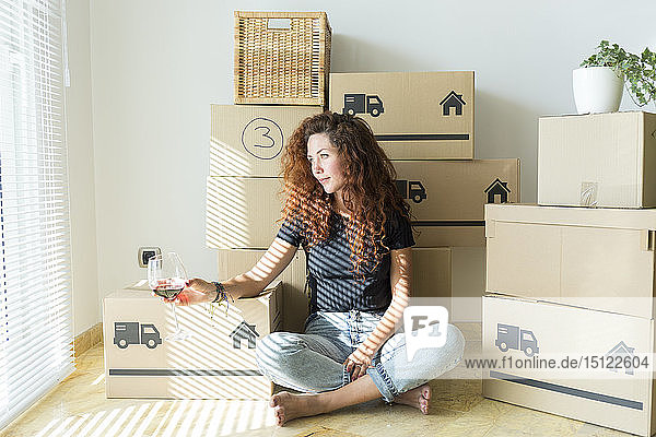 Young woman sitting in new home with glass of red wine