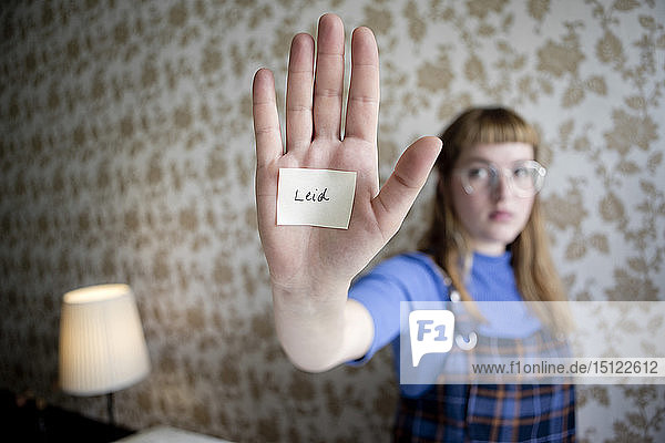 Studentin zeigt ihre Hand  einen Zettel mit dem Wort Leiden auf ihrer Hand