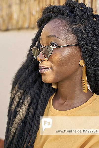 Porträt einer jungen Frau mit Nasenpiercing  Sonnenbrille und Dreadlocks