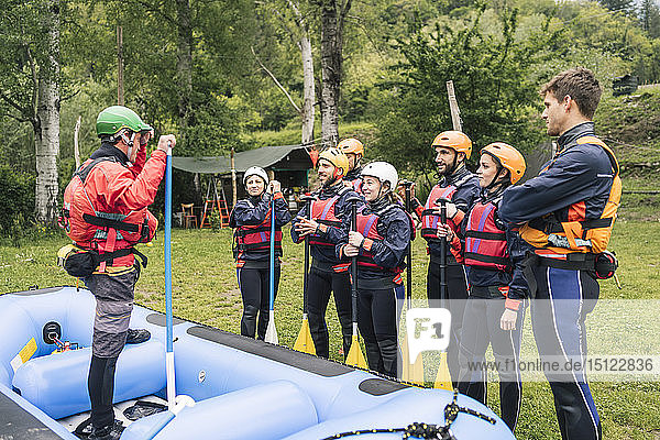 Ausbilder im Gespräch mit einer Gruppe von Freunden bei einem Rafting-Kurs