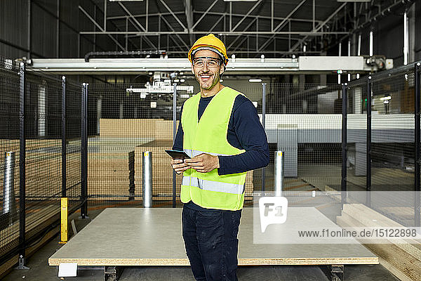 Porträt eines lächelnden Arbeiters mit Tablette im Fabriklager