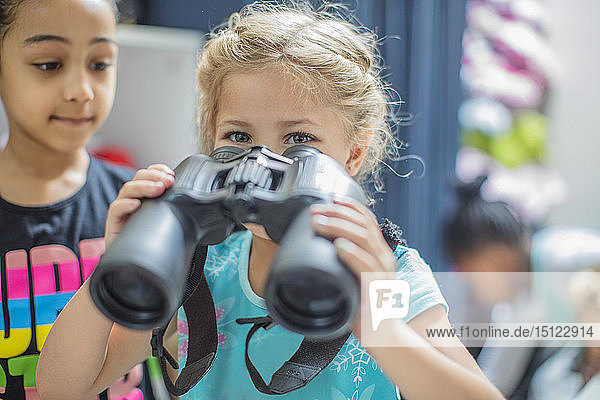 Girl holding binoculars in kindergarten