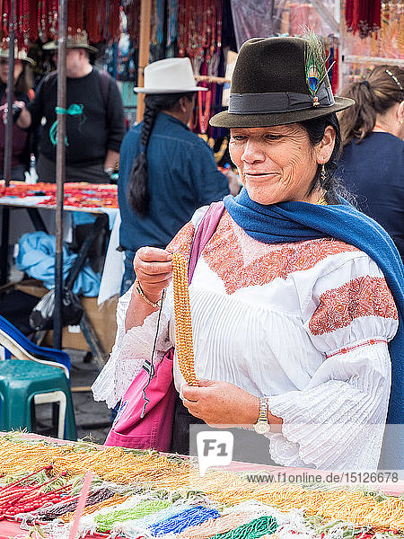 Indigenous woman buying gold necklace  market  Plaza de los Ponchos  Otavalo  Ecuador  South America
