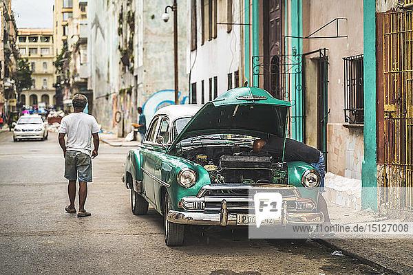 Einheimischer repariert seinen kaputten amerikanischen Oldtimer  La Habana (Havanna)  Kuba  Westindien  Karibik  Mittelamerika