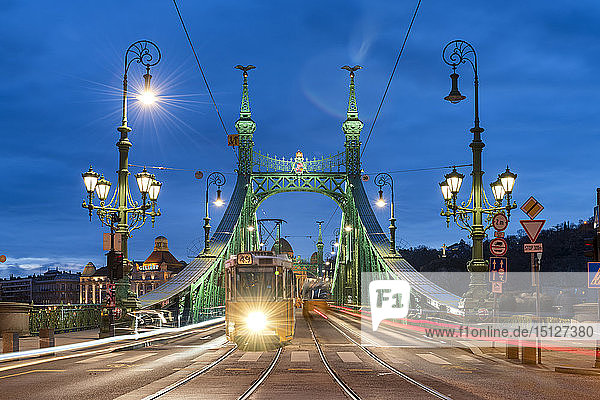 Straßenbahn über die nächtlich beleuchtete Freiheitsbrücke mit dem Hotel Gellert im Hintergrund  Budapest  Ungarn  Europa