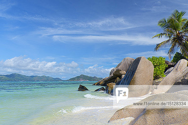 Waves swirling around large granite boulders and palm trees on Anse Source d'Argent La Digue Seychelles Indian Ocean Africa
