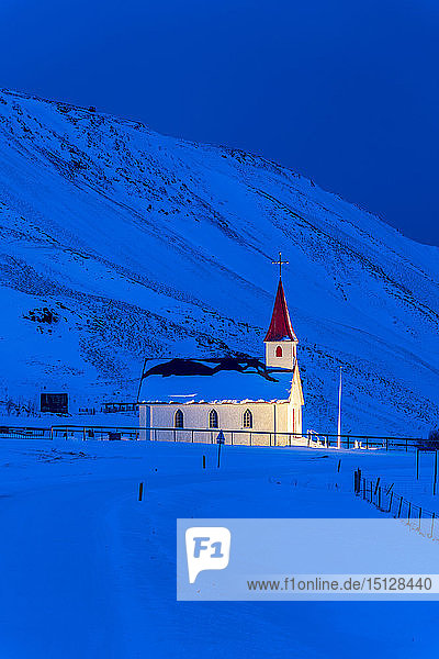 Beleuchtete Kirche in der Morgendämmerung vor schneebedeckten Bergen  Winter  bei Vik  Südisland  Island  Polarregionen