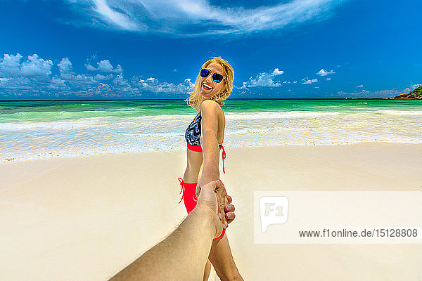 Glückliche Touristin im Bikini hält die Hand ihres Partners  Wild Anse Kerlan  Praslin  Seychellen  Indischer Ozean  Afrika