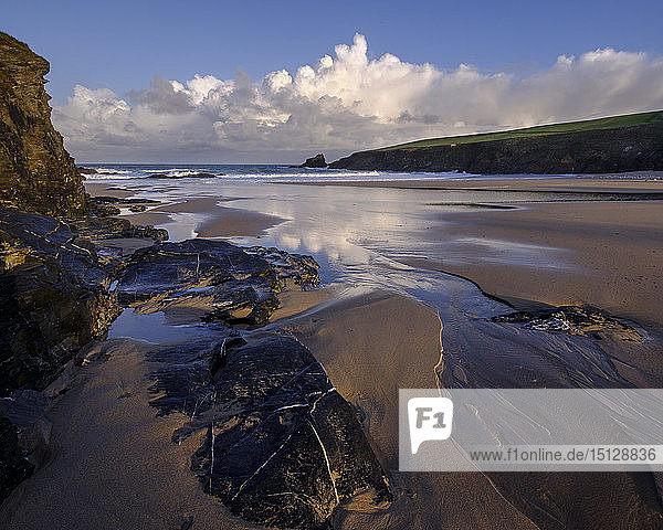 Atlantische Wolken reflektieren das Licht der Morgendämmerung auf den nassen Sand und die Felsen von Trevone in der Nähe von Padstow  Cornwall  England  Vereinigtes Königreich  Europa