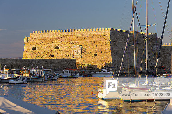 View across the Venetian Harbour  sunset  the Koules Fortress reflected in water  Iraklio (Heraklion)  Crete  Greek Islands  Greece  Europe