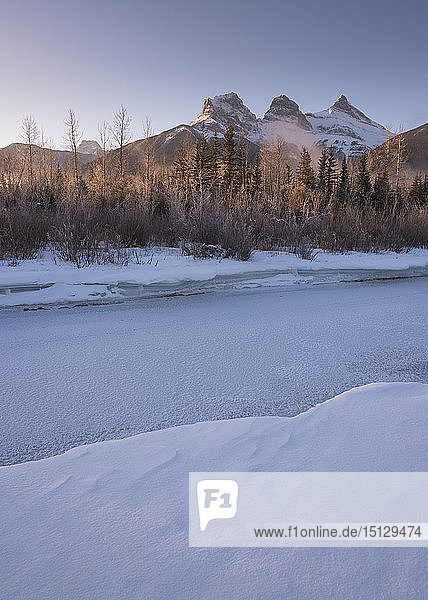 Winterlicher Sonnenaufgang mit gefrorenem Bow River und Three Sisters  Canmore  Alberta  Kanadische Rockies  Kanada  Nordamerika