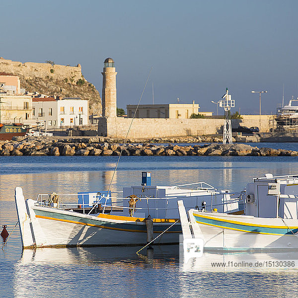 Fishing boats moored in the bay  early morning  historic lighthouse in background  Rethymno (Rethymnon)  Crete  Greek Islands  Greece  Europe