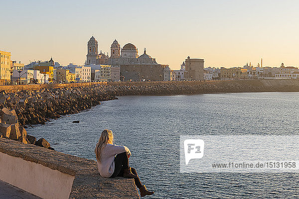 Frau genießt den Blick auf die Kathedrale von Santa Cruz und das Meer von der Uferpromenade aus gesehen  Cadiz  Andalusien  Spanien  Europa