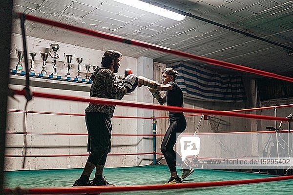 Boxer sparring with trainer in boxing ring