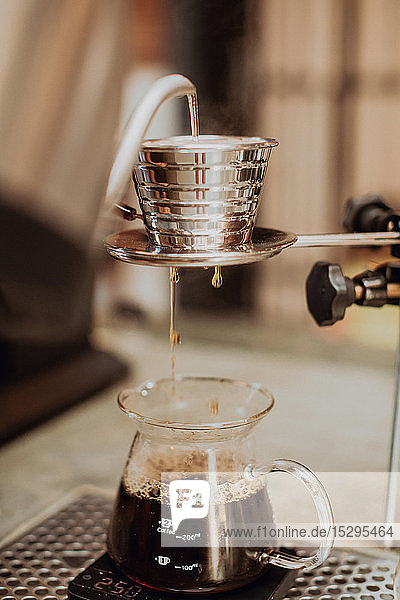 Gekochtes Kesselwasser  das in den Kaffeefilter läuft und in die Kanne auf der Kaffeetheke tropft  Nahaufnahme  flacher Fokus
