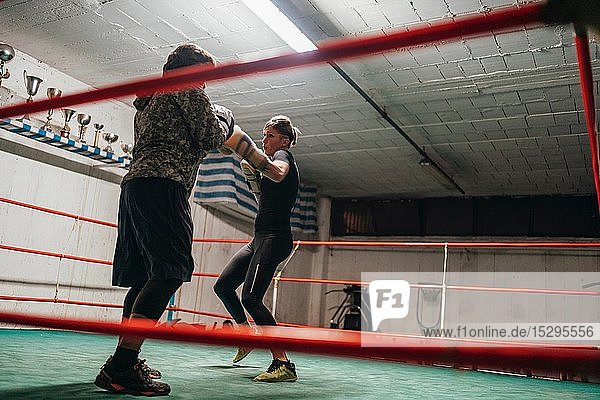 Boxer sparring with trainer in boxing ring