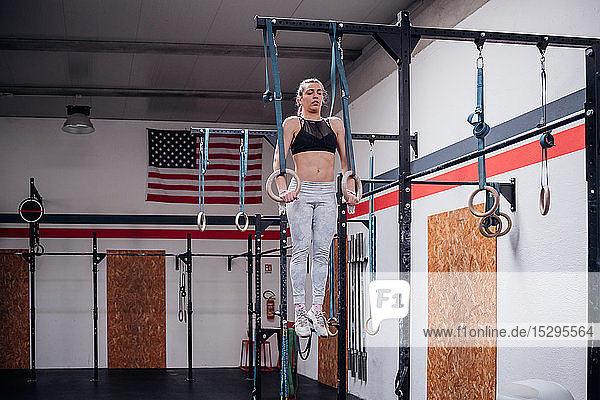 Young woman balancing on gymnastic rings in gym