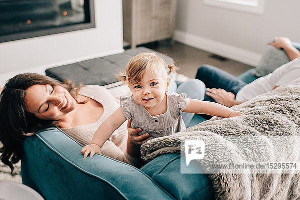 Mother playing with baby daughter on sofa  portrait