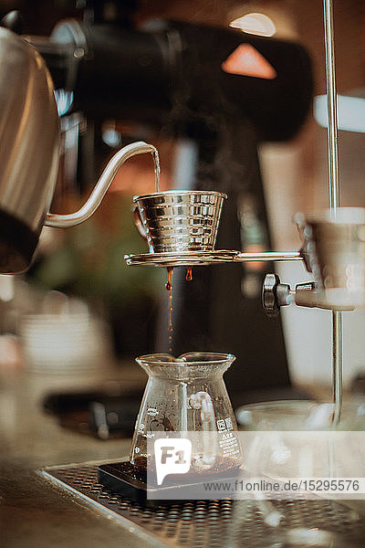 Gekochtes Kesselwasser  das in den Kaffeefilter läuft und in die Kanne auf der Kaffeetheke tropft  flacher Fokus
