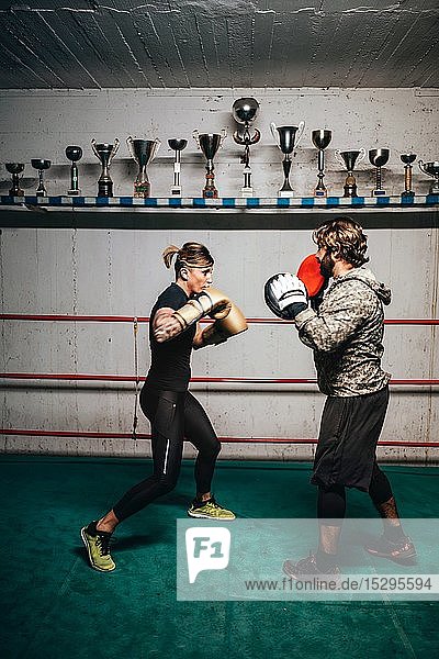 Boxer sparring with trainer in boxing ring