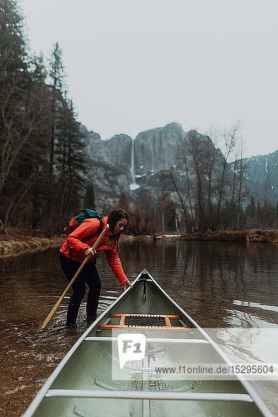Young female canoeist pulling canoe in river  Yosemite Village  California  USA