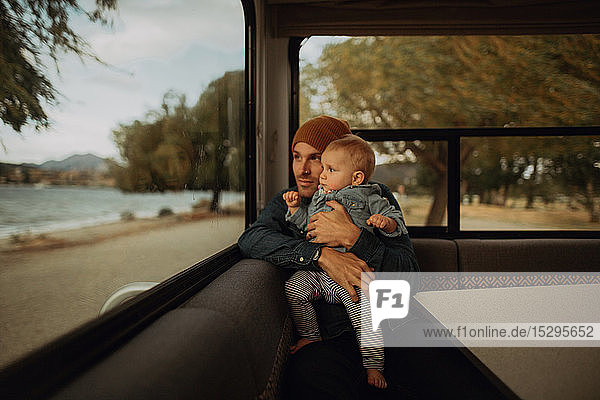 Vater und Baby schauen aus dem Fenster eines Wohnmobils  Wanaka  Taranaki  Neuseeland