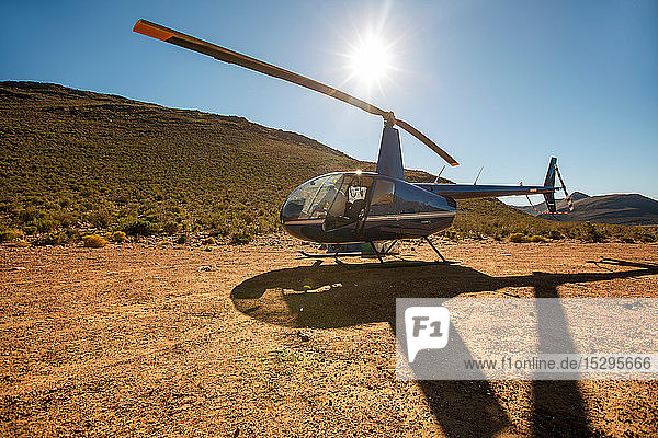 Hubschrauber und Pilot in sonnenbeschienener ländlicher Landschaft  Kapstadt  Westkap  Südafrika