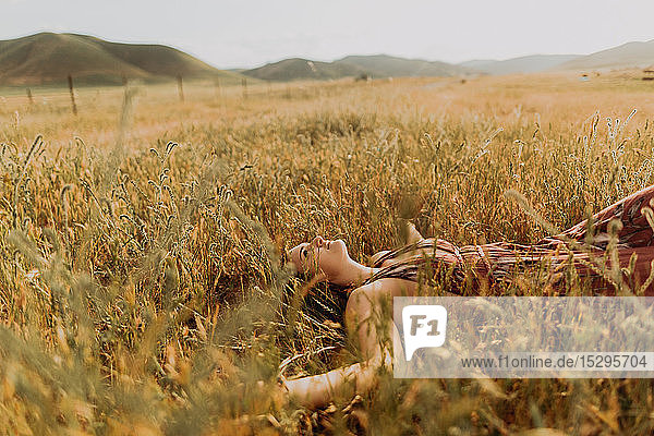 Junge Frau liegt im Feld aus langem Gras  Exeter  Kalifornien  USA