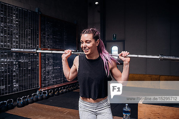 Young woman lifting weight bar in gym