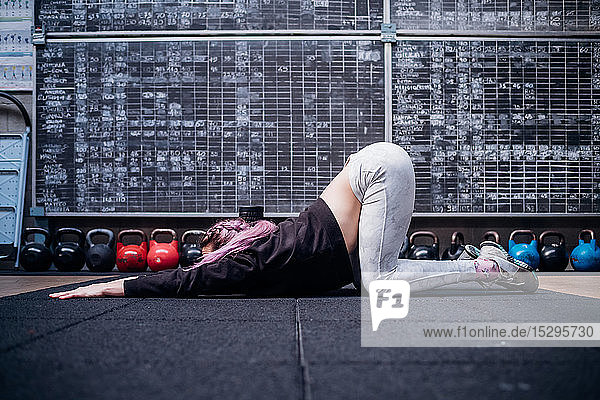 Young woman stretching upper body in gym
