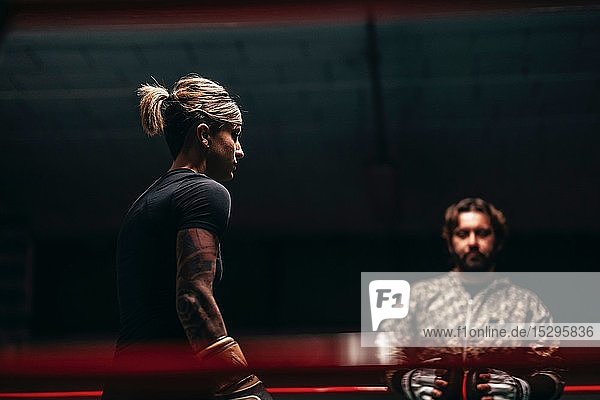 Boxer sparring with trainer in boxing ring