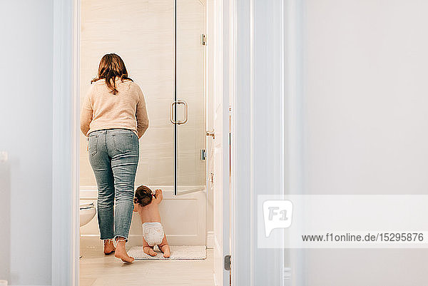 Mother with baby daughter preparing bath  rear view