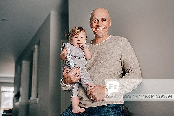 Father carrying baby daughter in hallway  portrait