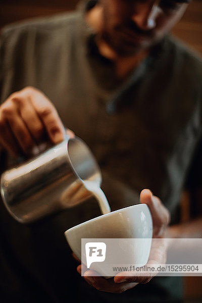 Barista gießt Milch in Kaffeetasse im Café  abgeschnittener flacher Fokus