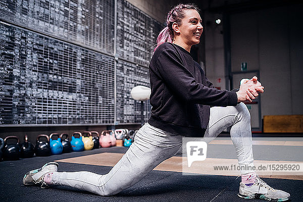 Young woman stretching legs in gym