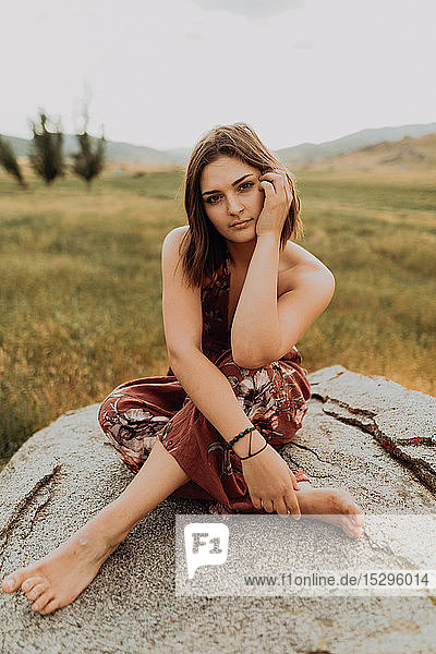 Schöne junge Frau sitzt im Schneidersitz auf einem Felsblock  Portrait  Exeter  Kalifornien  USA