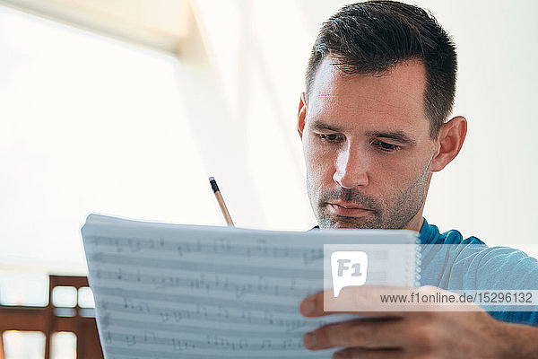 Mid adult man reading acoustic guitar sheet music close up