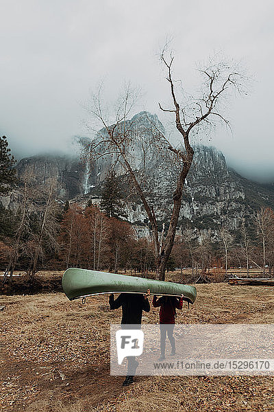 Junges Kanu-Ehepaar trägt Kanu über Kopf in Berglandschaft  Yosemite Village  Kalifornien  USA