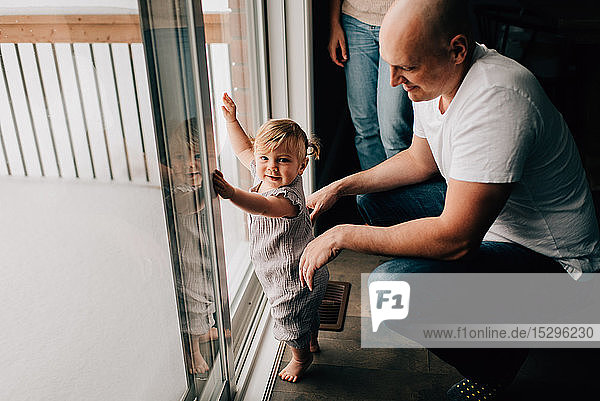 Mother and father with baby daughter at patio door